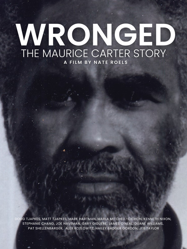 A black and white movie poster features a serious bearded mans face with the large title Wronged The Maurice Carter Story and production credits overlaid.